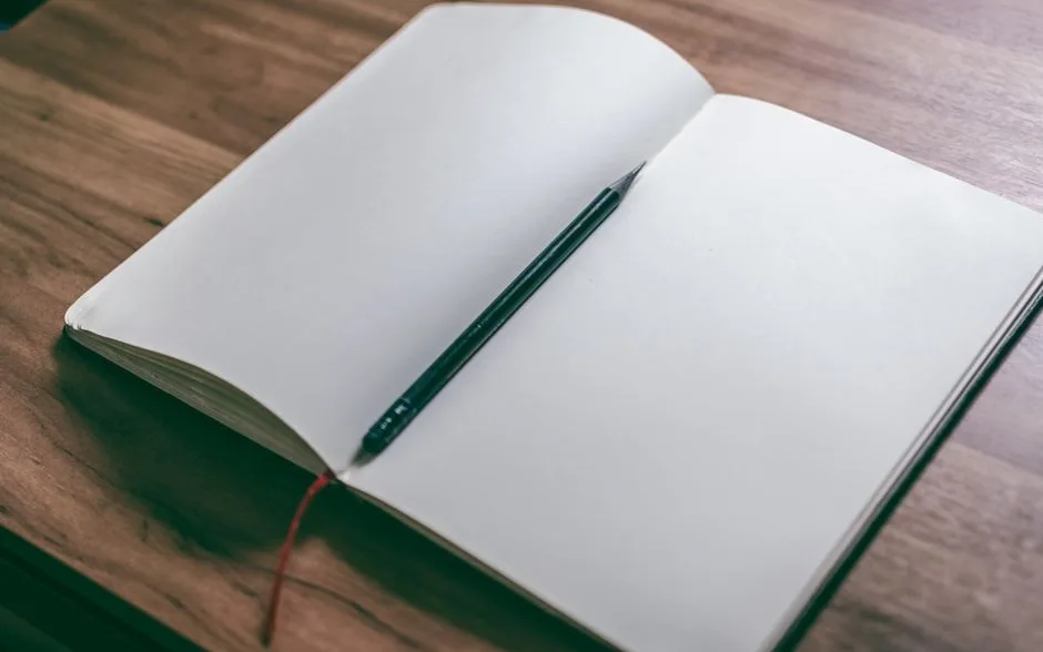 Carnet ouvert et crayon posés sur une table en bois