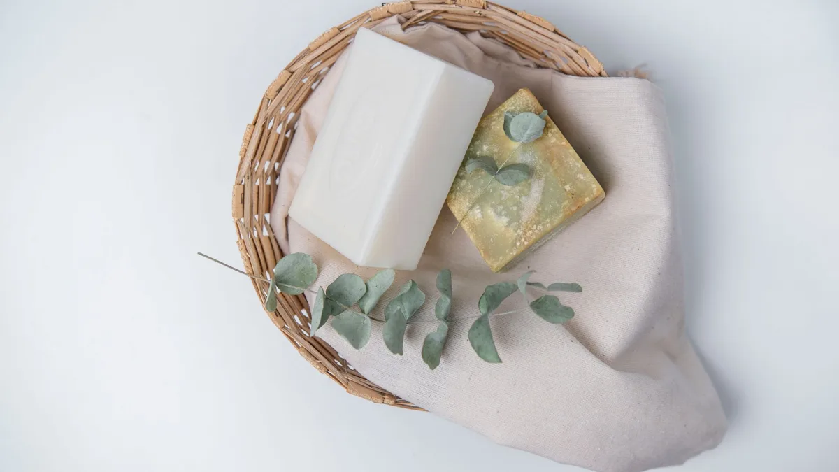 Flacon de savon noir liquide posé sur une table en bois, à côté d'un chiffon et d'une plante verte
